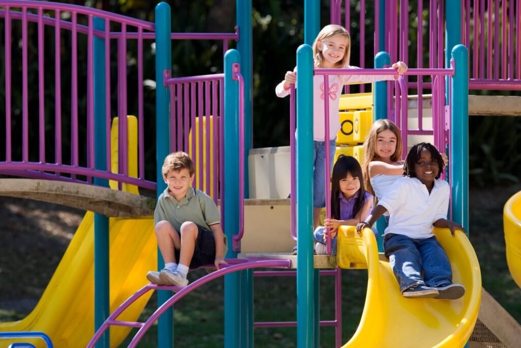 A group of diverse children enjoying playground slides on a sunny day outdoors.