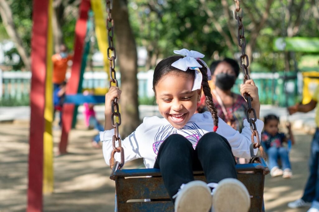 Smiling young girl with braided hair enjoying a swing ride outdoors.