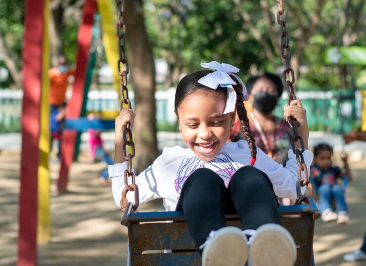 Smiling young girl with braided hair enjoying a swing ride outdoors.